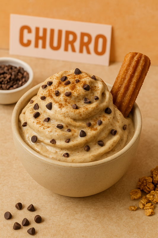 A creamy bowl of churro-inspired nice cream topped with cinnamon, chocolate chips, and a churro stick, styled with warm tones for a fun dessert vibe.